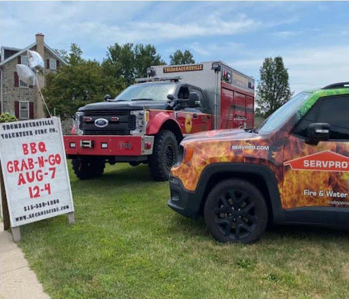 A SERVPRO car and Fire Vehicle parked by a sign for “Grab and Go BBQ”