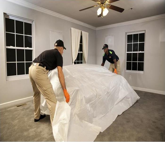 2 techs covering and moving a piece of furniture in a living room