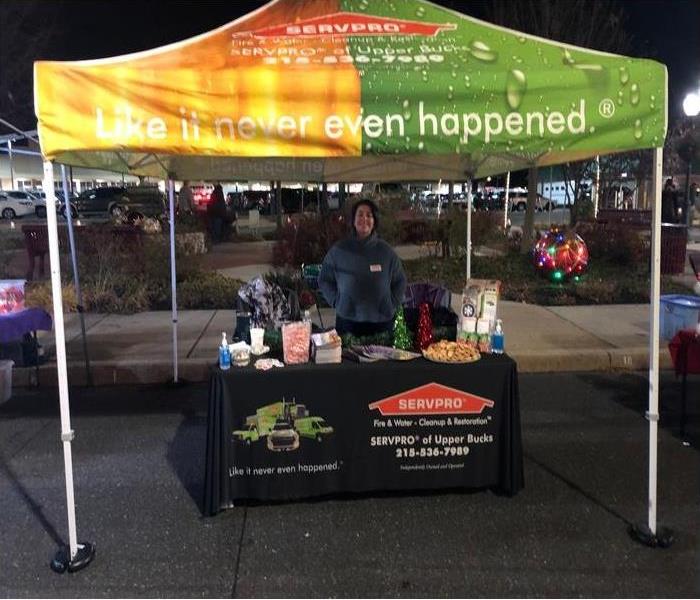 a woman standing behind a table with a SERVPRO tent overhead